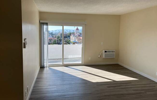 A room with a view of a city through the sliding glass door.