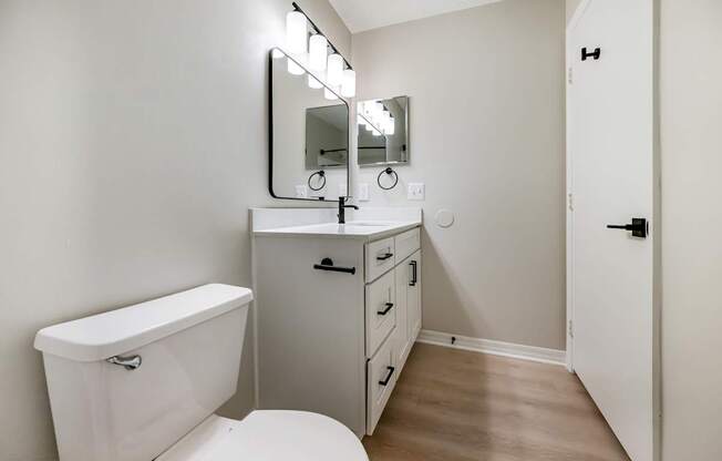 A white bathroom with a toilet, sink, and mirror.