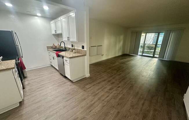 A kitchen with white cabinets and a wooden floor at Willow Tree Apartments, California, 90505