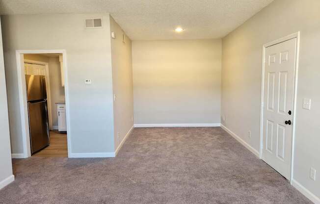 A room with a carpeted floor and a white door. The Cloisters Apartments, 902 67th Avenue North, Myrtle Beach, SC
