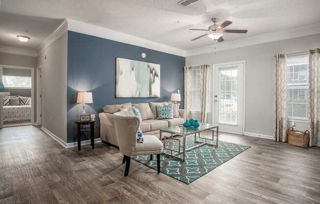 A living room with a beige couch, a coffee table, and a ceiling fan.