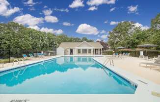 a pool with lounge chairs and a house in the background