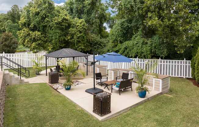 A backyard with a white fence and a patio with a table and chairs.