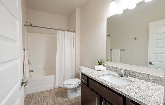 a bathroom with a sink toilet and shower and a mirror at Technology Park Apartments, Rochester, Minnesota