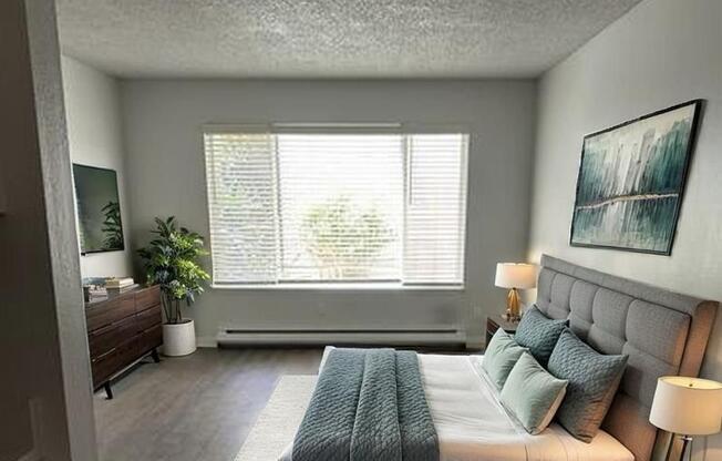 A bedroom with a large bed and a window with blinds.