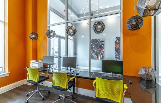 an office with orange walls and a black desk with yellow chairs