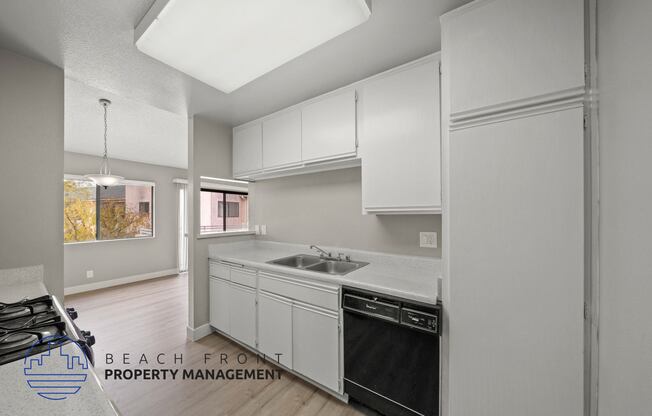 a white kitchen with white cabinets and a black dishwasher