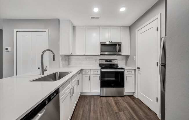 an empty kitchen with white cabinets and stainless steel appliances