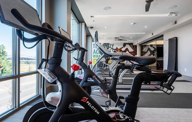 a gym with several bikes in a room next to a window