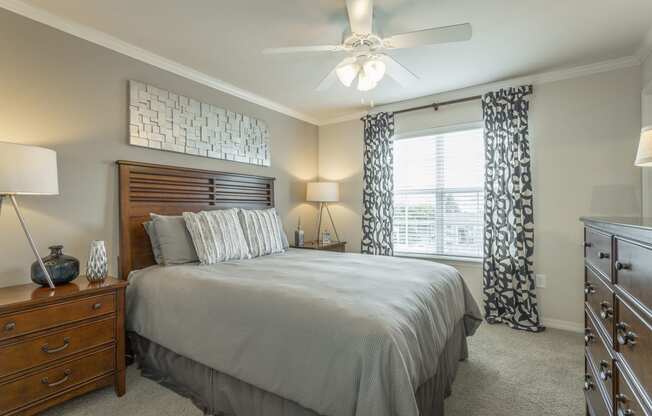 Beautiful bedroom at Amberleigh Ridge with plush carpeting, overhead lighting, designer ceiling fan and large windows