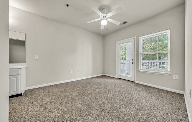 an empty living room with a ceiling fan and a window