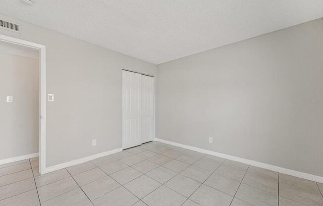 A room with a white door and tiled floor.