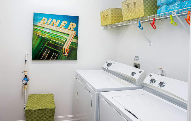 a laundry room with two washing machines and a painting on the wall