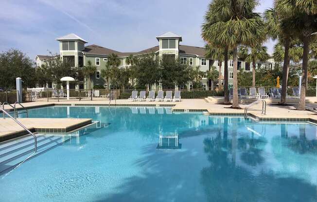 A large swimming pool in front of a building with palm trees.