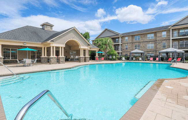 A large swimming pool in front of a building with a patio area.