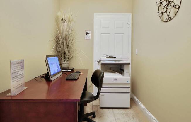 A room with a desk, computer, and printer.