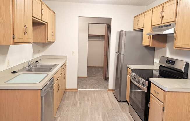 an empty kitchen with wooden cabinets and stainless steel appliances