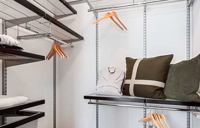 a walk in closet with shelving and a bench with pillows