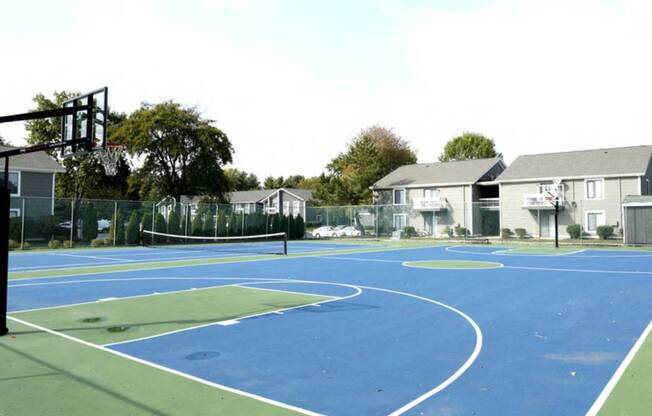 a blue and green basketball court with houses in the background