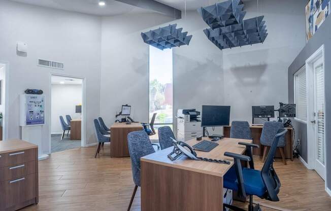 A modern office space with wooden desks and blue chairs.