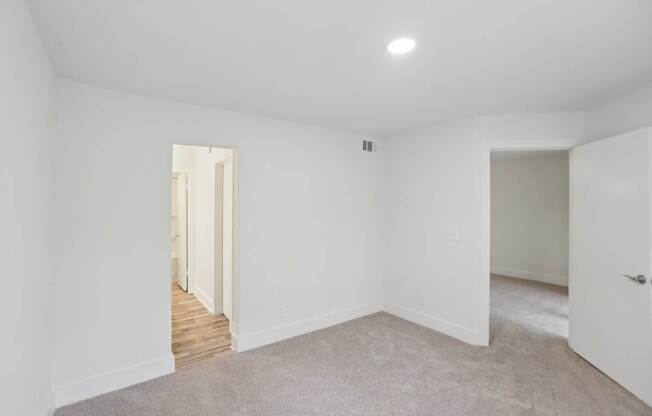 A bedroom with a carpeted floor and white walls.
