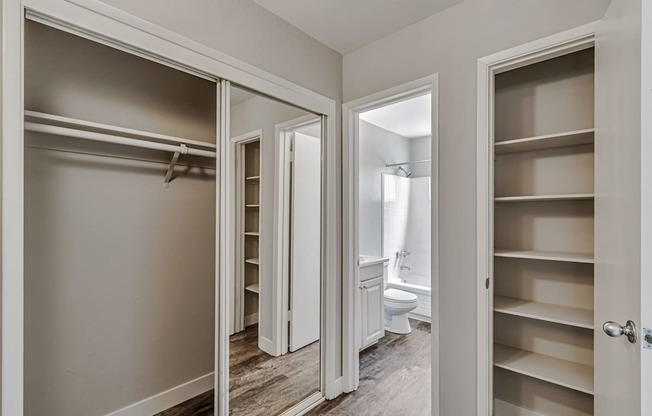 A white closet with shelves and a mirrored door.