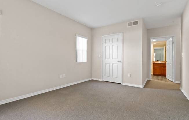 an empty living room with a white door and a bathroom