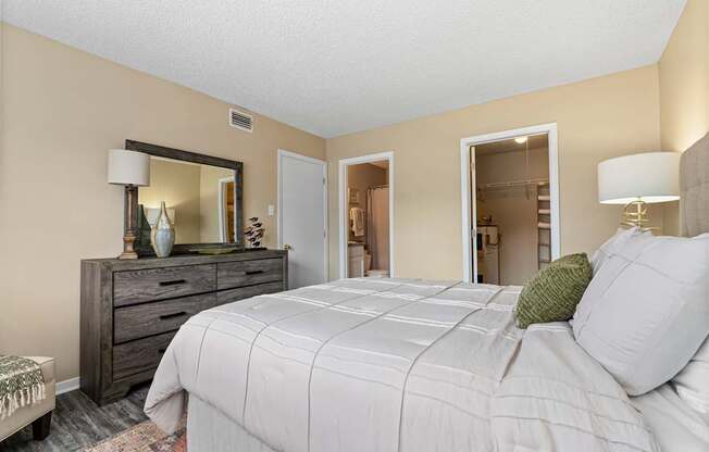 A bedroom with a large bed, a dresser, and a mirror.