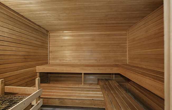 A wooden sauna with benches and a heating element on the floor.