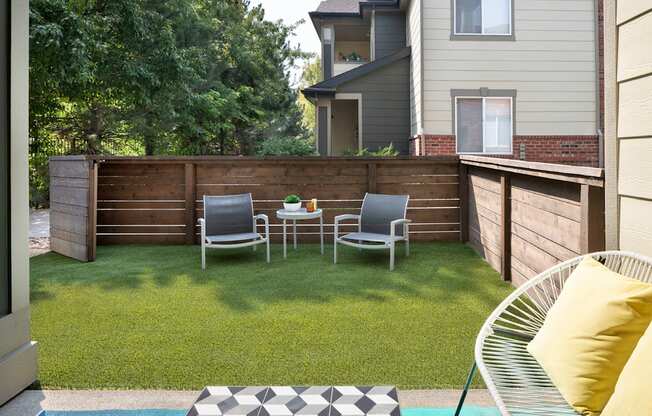 a backyard with a wooden fence and a patio with two chairs and a table