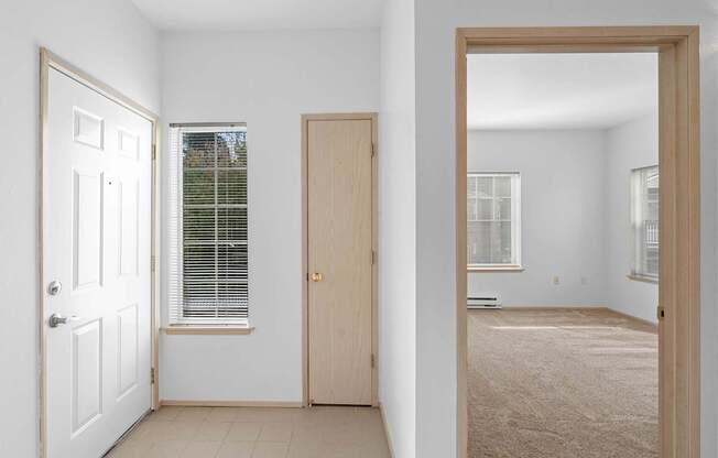 an empty room with a door to a bedroom and a window