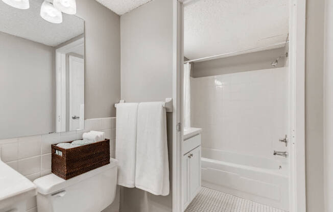 White bathroom with bright lights and the camera facing the bathtub and shower