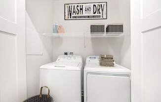 A laundry room with a washer and dryer and a sign at Strathmore Apartment Homes, West Des Moines, 50266