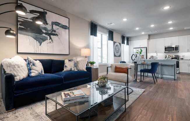 A modern living room with a dark blue sofa and a glass coffee table.