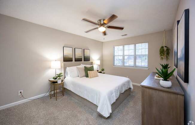 A bedroom with a bed, nightstand, and a ceiling fan.