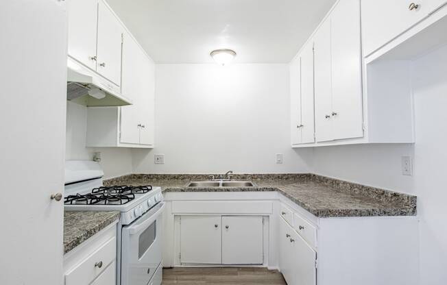 an empty kitchen with white cabinets and granite counter tops