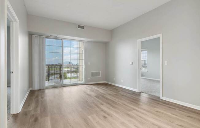 A spacious room with wooden flooring and a view of the city through the window.