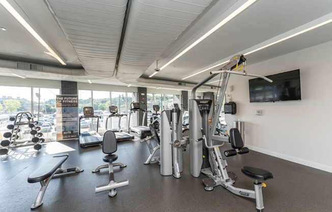 a gym with weights and cardio equipment and a view of the city