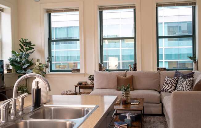 a living room with a couch and a kitchen with windows