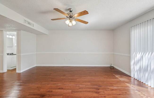 A room with a ceiling fan and wooden flooring.