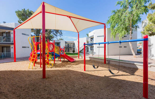 a playground with a swing set and monkey bars in front of a building