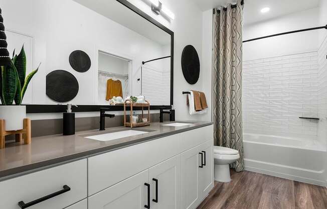 A white bathroom with a wooden floor and a white tub.