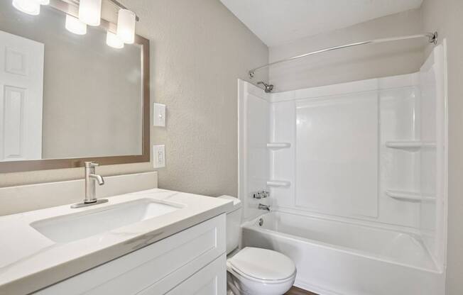 A white bathroom with a sink, toilet, and bathtub.
