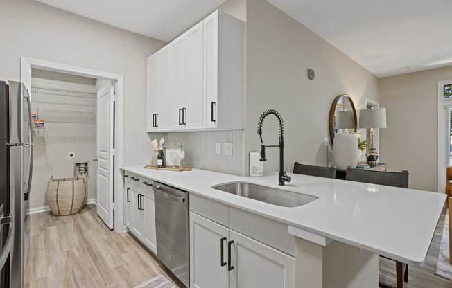Flatiron West Trade Apartments staged model unit kitchen connected to living room with stainless steel modern appliances and quartz countertops