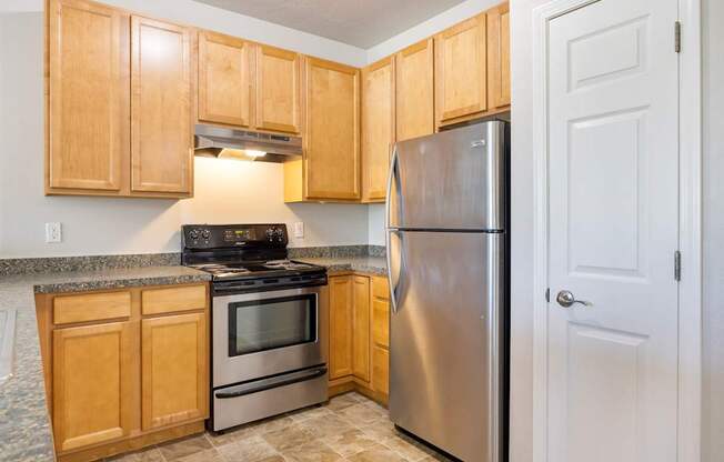 A kitchen with wooden cabinets and a stainless steel refrigerator.