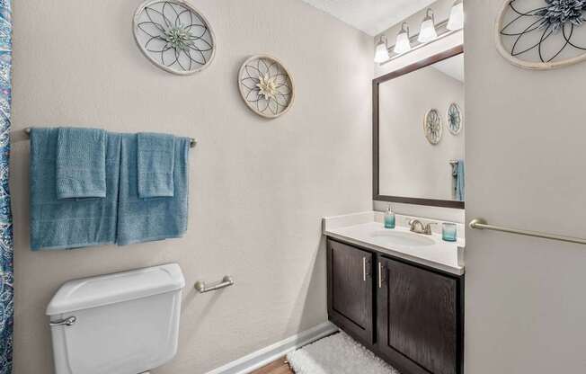 A bathroom with a toilet, sink, and mirror.