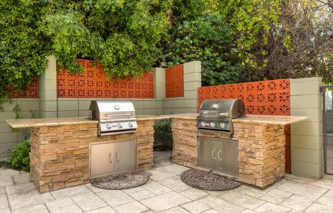 Encino Apartments for Rent - Community Outdoor BBQ Area with Two Grills, Built in Counters, and Surrounded by Lush Landscaping.
