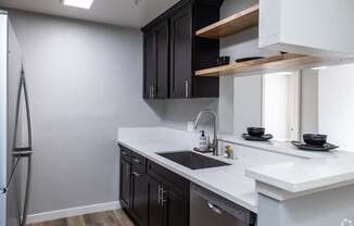 A modern kitchen with black cabinets and white countertops.