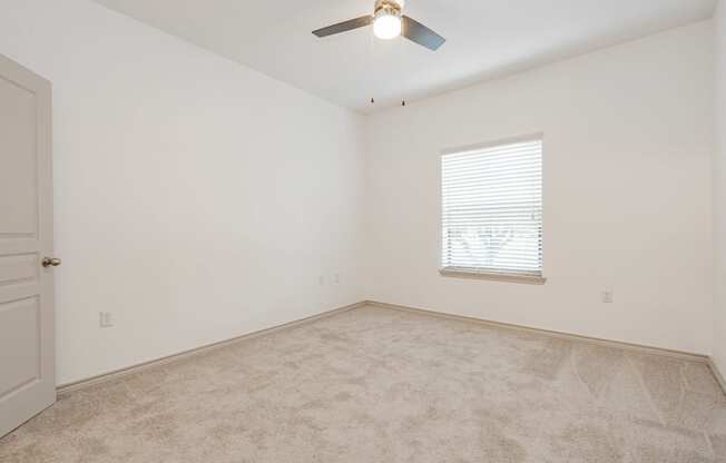 an empty room with a ceiling fan and a window