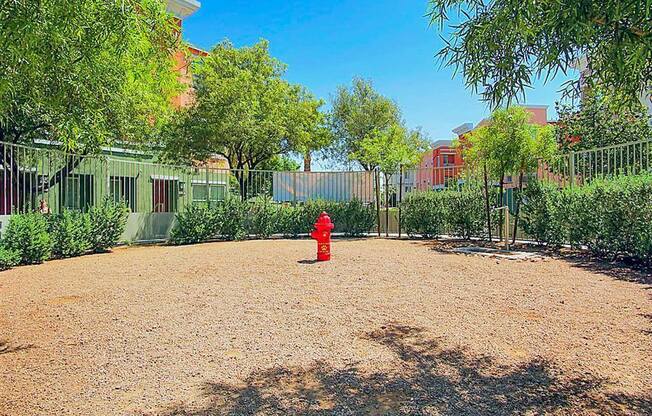 A red fire hydrant sits in the middle of a gravel lot.